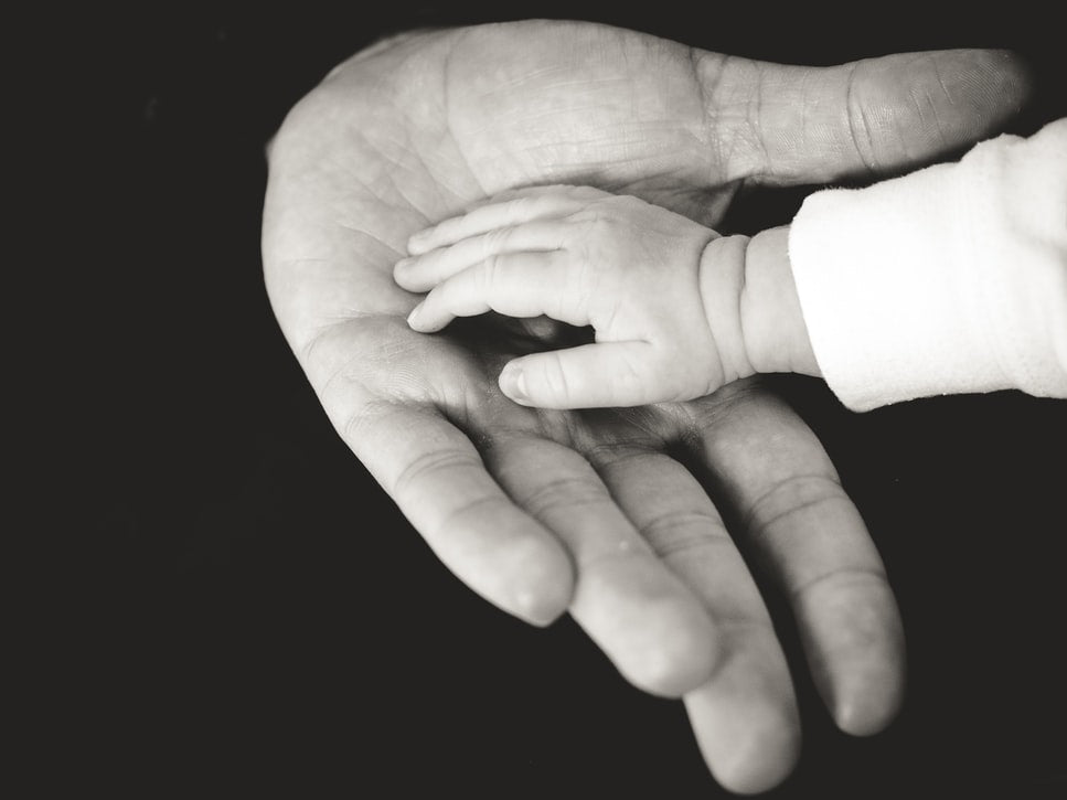 Image of a baby's hand resting on an adult hand